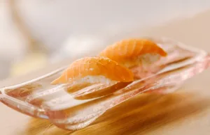 Raw salmon slices on a glass plate, served on a wooden table