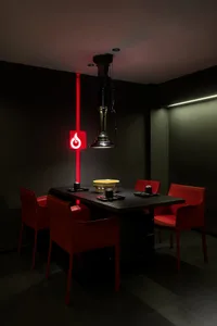 Dining space with a black table and red chairs, set for a meal with a bowl on the table, in a modern and stylish atmosphere