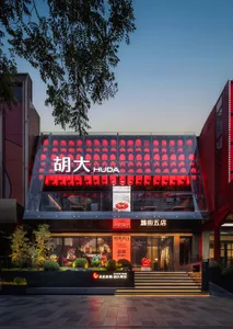 A modern Asian storefront at night with a glass front, featuring comfortable seating and a stylish interior
