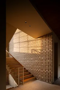 A modern staircase with wooden steps and patterned wallpaper, near a window with natural light