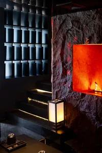Warm and inviting interior space with a red accent wall, a staircase, and a bottle on a surface, lit by two lamps