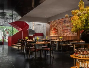 A restaurant dining area with multiple tables and chairs, potted plants, and an inviting atmosphere