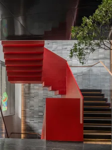 A modern building with two sets of red-stained wood stairs and railings, set against a neutral background