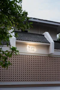 Modern building with a white concrete facade, tile roof, and several windows with shutters, set against a calm and serene background