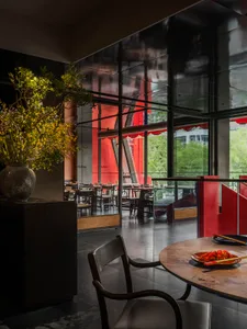 A cozy restaurant dining area with tables, chairs, and potted plants, creating a warm and inviting atmosphere
