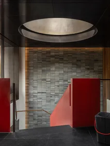A hotel lobby staircase with red brick stairs, stone walls, and warm lighting creating a cozy atmosphere