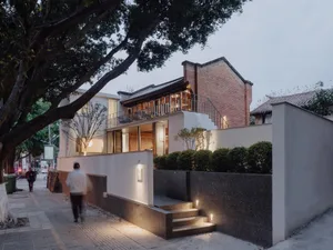 A modern house with a large white wall, a black staircase, and a brick exterior, set in a calm and serene environment