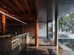 Modern restaurant interior with a large wooden beam, black and white color scheme, and multiple dining tables