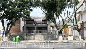 A traditional building with a brick facade and outdoor seating area, surrounded by a tree and a parked truck