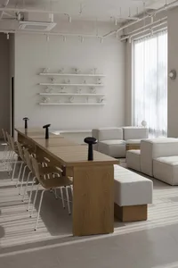 A modern living room with a wooden dining table surrounded by eight chairs, set against a backdrop of white walls and a clean, minimalist design