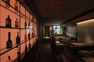 A sophisticated bar area with wine bottles, chairs, and potted plants, creating a warm and inviting atmosphere