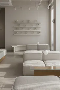 A well-lit living space with a large couch, glass table, and two chairs, surrounded by inviting decor