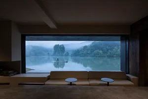 Cozy living space with a large couch, a window overlooking a serene lake, and a comfortable seating arrangement