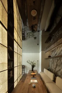 A well-lit living area with a dining table, chairs, books, and a vase, creating a warm and inviting atmosphere