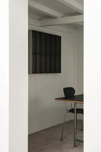 A clean and organized office space with a black desk, two chairs, and a cup, set against a white background