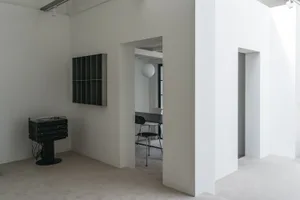 Empty minimalist room with a dining table and chairs, and a doorway leading to another room
