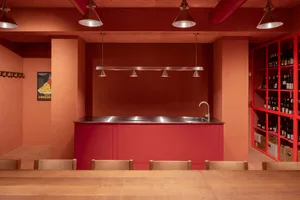 Modern kitchen with a red-painted wall, a dining table, and three chairs, near a sink and countertop