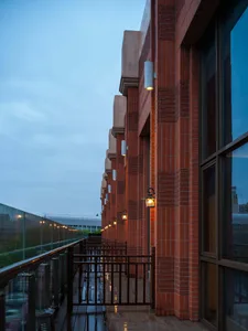 A traditional building with red brick walls, a glass railing on the balcony, and warm lighting creating a cozy atmosphere