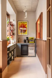 Modern kitchen with a sink, oven, and refrigerator, featuring two potted plants and a well-lit atmosphere