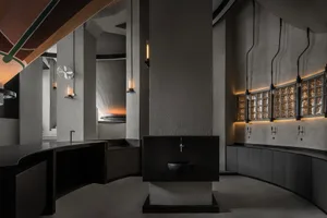 Empty modern bathroom with a black sink and a large stone wall, illuminated by a few lights