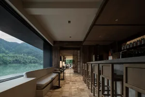 A bar area with stools and chairs, surrounded by dining tables in a stylish restaurant setting