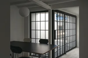 A well-lit dining space with a black table surrounded by chairs and a couch near the left wall