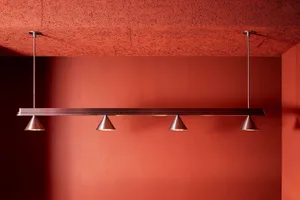 A warm and inviting room with an orange wall, brick texture, and soft lighting from hanging silver fixtures