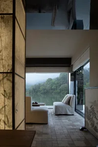 Comfortable living space with a couch, chair, and table in front of a large window, adorned with Asian artwork and well-lit