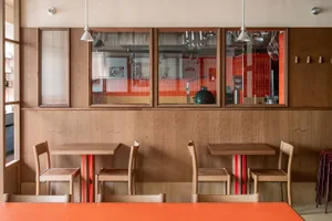 Cozy dining space with wooden tables and chairs, a vase on one table, and warm atmosphere