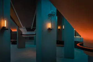 A dimly lit industrial space with concrete pillars and walls, creating a mysterious atmosphere