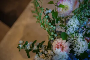 A bouquet of pink and white flowers in a vase on a table, creating a visually appealing display with a warm and inviting atmosphere