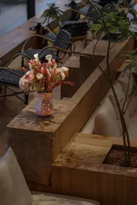 A cozy indoor space with a vase of flowers on a table, surrounded by chairs and a dining table