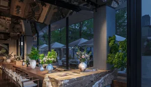 Elegant dining space with a stone countertop, vases, umbrellas, and natural elements, designed for socializing or dining