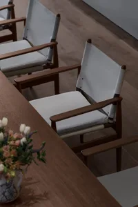 Empty dining area with a wooden table and six chairs, a vase on the table, and warm lighting
