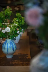 Warm and inviting dining space with a wooden table, chairs, vases, a bowl, and a cup, creating an intimate atmosphere