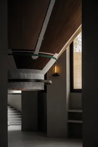 A modern lobby with a circular structure, concrete walls, a wooden dome ceiling, and a light fixture