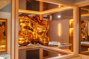 Elegant showroom with a gold metal sculpture, chairs, and decorative bottles, set against a sophisticated backdrop