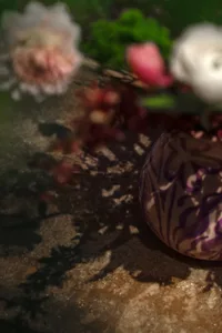 A glass vase with a purple design holds flowers in a calm and inviting indoor setting