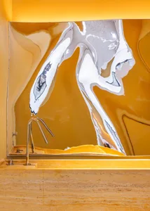 A bathroom sink area with a yellowish hue, featuring a prominent sink and mirror