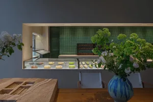 麵包店內部，玻璃櫥窗展示各式蛋糕、花瓶插花，營造溫馨氛圍