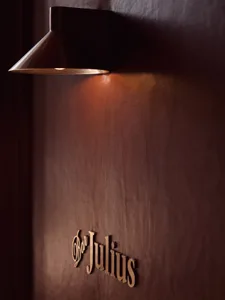 A brown wall with a metal lamp attached, lit up in a minimalist setting