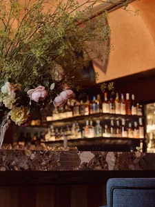 A cozy bar scene with a counter, flowers, and bottles, creating an inviting atmosphere