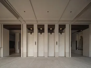 Empty hallway with concrete walls, three doors, and light fixtures above each door