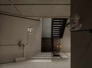 A stone staircase in a museum with two candles on the steps, surrounded by artwork and a calm atmosphere