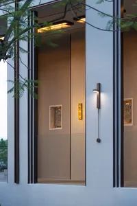 Two wooden doors in a hotel lobby with lights above each door, creating a welcoming atmosphere