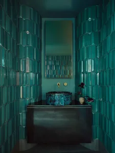 A clean and well-organized bathroom with a sink, mirror, and toilet, featuring decorative vases on the countertop and a blue-framed mirror