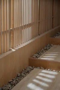 A calm and inviting interior space with wooden walls and floors, featuring a staircase leading up to a higher level