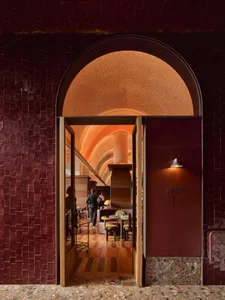 A cozy restaurant interior with red brick walls, several tables, and chairs, creating a warm and inviting atmosphere for patrons