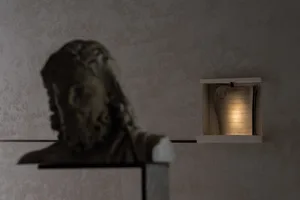 A marble statue of a man's head on display in a museum or gallery setting with a focus on artistic appreciation and historical significance