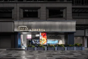 Modern Asian restaurant with large windows, potted plants, gray and white elements, and a welcoming atmosphere